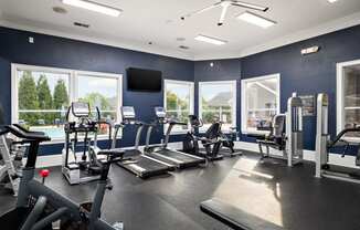 a gym with cardio equipment and windows with a view of a pool