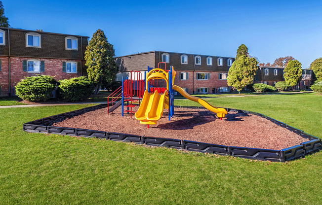 a playground in the middle of a grassy area with a building in the background