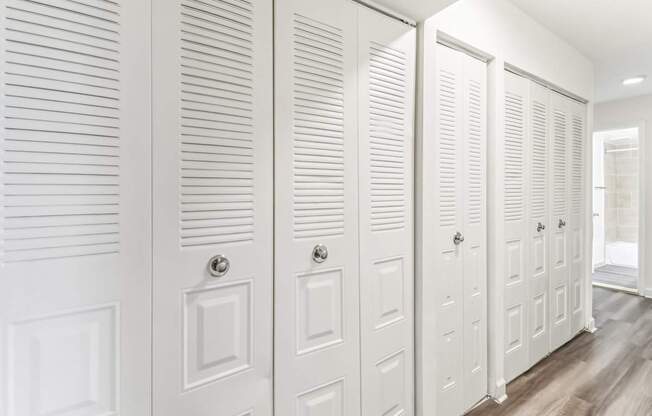 a row of white closet doors in a room with wood floors