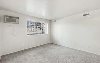 A garden style living room with a window showing trees outside at Trappers Cove Apartments, Lansing