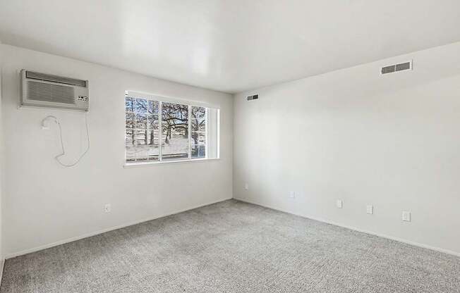 A garden style living room with a window showing trees outside at Trappers Cove Apartments, Lansing