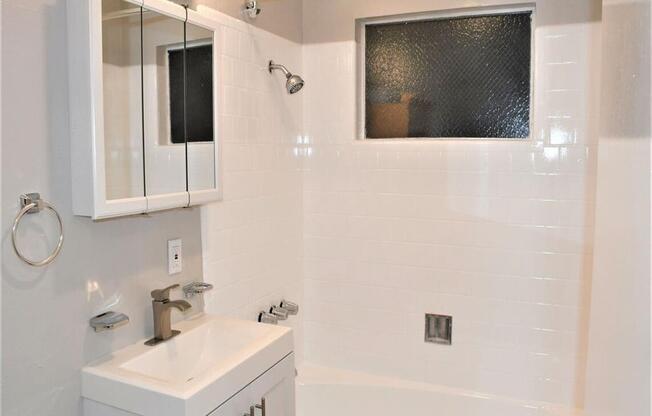 a white bathroom with a sink and a bath tub