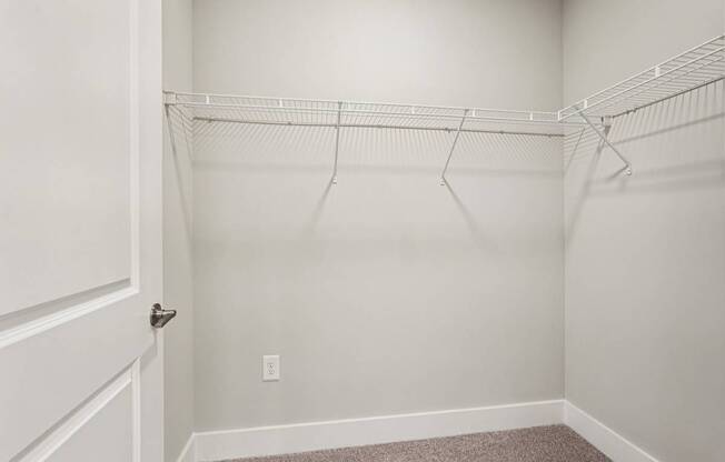 A white closet with a carpeted floor and a white door.