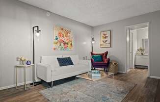 A living room with a white couch, a chair, and a painting on the wall.
