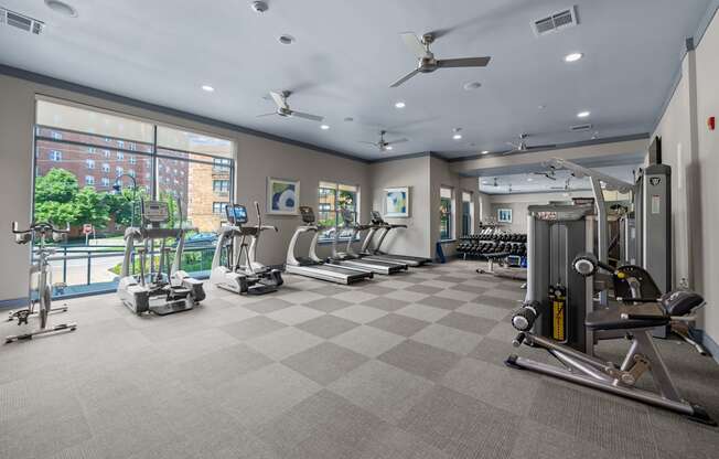 A spacious gym with a variety of equipment and a view of a city skyline.
