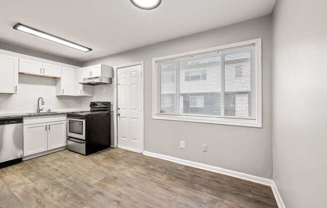 an empty kitchen with a large window and white cabinets and appliances