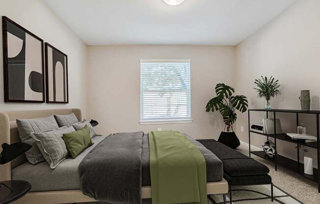 Pet-Friendly Apartments in Houston, TX – Artisan West – A bedroom with a bed, a green blanket, and a potted plant.