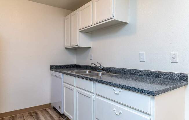 A kitchen with white cabinets and a granite countertop.
