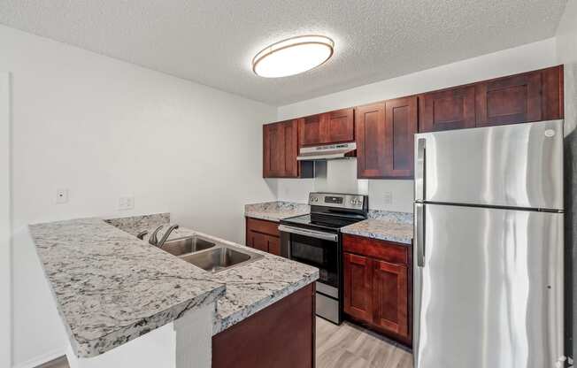 a kitchen with granite counter tops and a stainless steel refrigerator