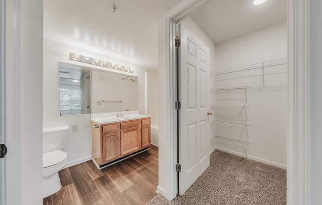 A bathroom with a white tub and sink, a wooden cabinet, and a white door.