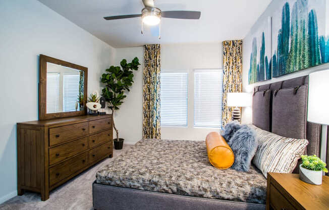 A bedroom with a bed, dresser, and a ceiling fan.