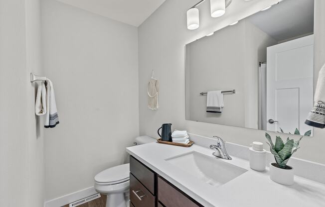 a bathroom with a sink and a toilet and a mirror at The Residences Apartments at Bear Tree | DeForest, WI, DeForest Wisconsin