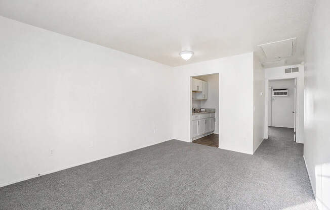 A white room with a grey carpet and a door on the right.
