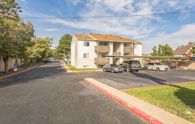 the view of an apartment building with cars parked in a parking lot