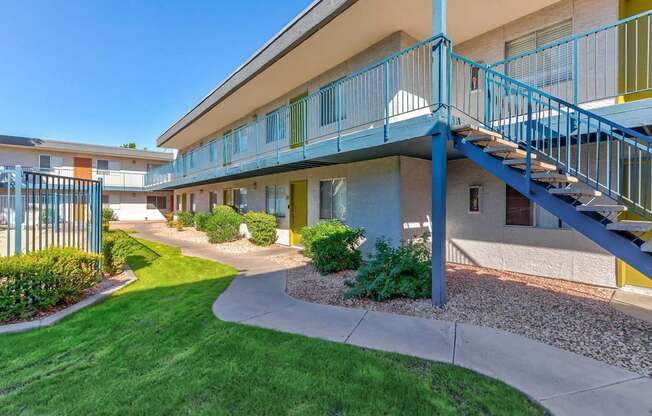 A blue and yellow building with a staircase leading to the second floor.