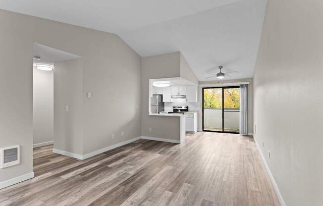 A spacious room with a kitchen area and a ceiling fan.