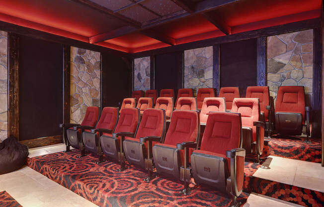 a room with a row of red chairs in front of a large stone wall