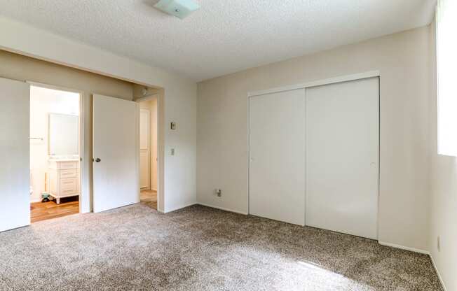 an empty bedroom with white closets and a carpeted floor