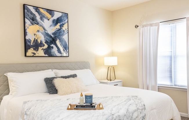 a bedroom with a white bed and a painting on the wall