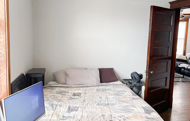 a bedroom with a bed and a computer on a desk