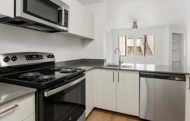 A modern kitchen with a black stove top oven and white cabinets.