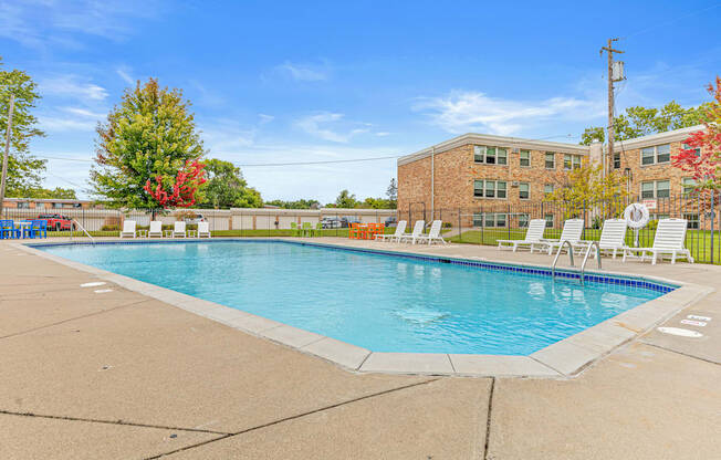 A swimming pool in front of a brick building with trees in the background.
