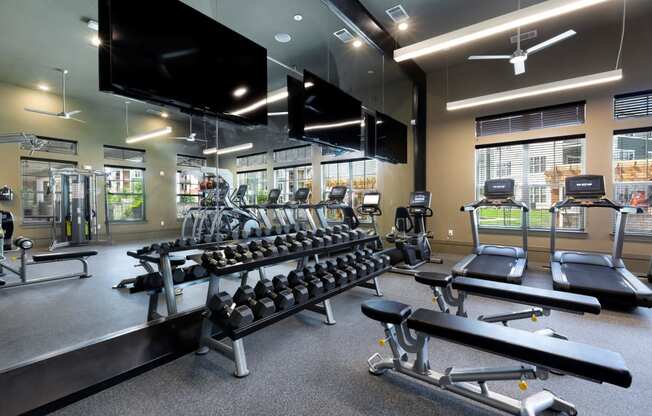 a gym with a row of weights and a large mirror