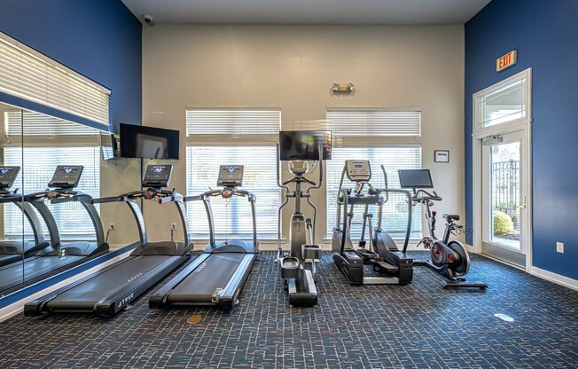 A gym with treadmills, elliptical machines, and stationary bikes.