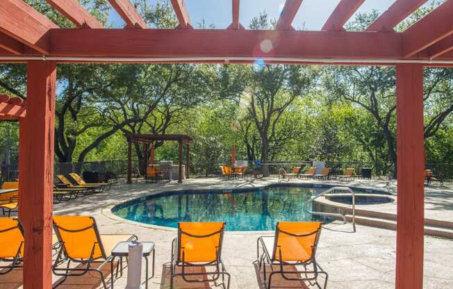 Swimming pool with lounge seating at Chisholm Place Apartments in Plano, TX