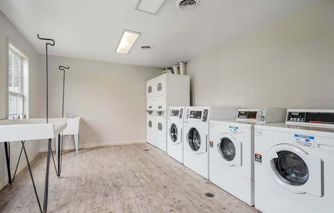 A laundry room with a white table and a row of washing machines.