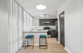 A kitchen with a bar stool in front of it.