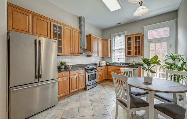 A kitchen with a refrigerator, oven, and a table with chairs.