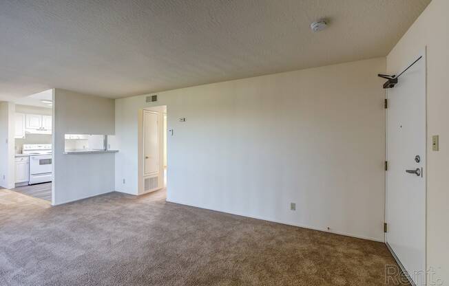 an empty living room with a kitchen in the background at Terrace View Apartments, Daly City 