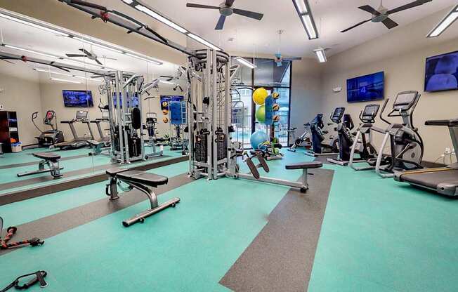 Gym with a variety of equipment including treadmills, weights, and exercise machines at Civic at Frisco Square Apartments, Frisco, Texas