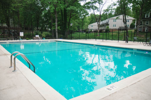 a large swimming pool with a fence around it and a house in the background