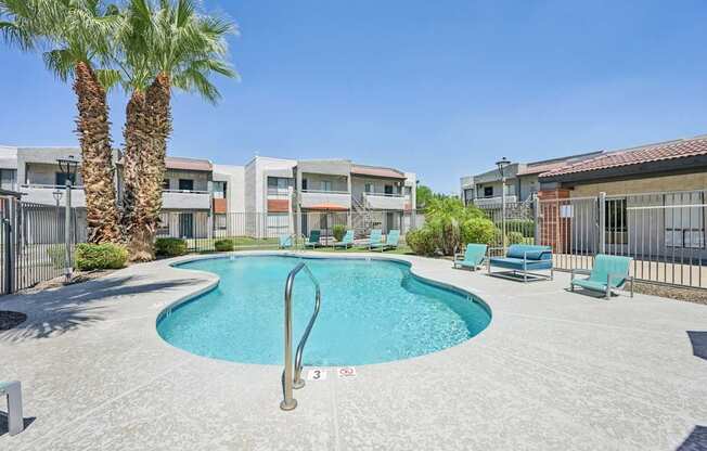 A swimming pool surrounded by palm trees and lounge chairs.