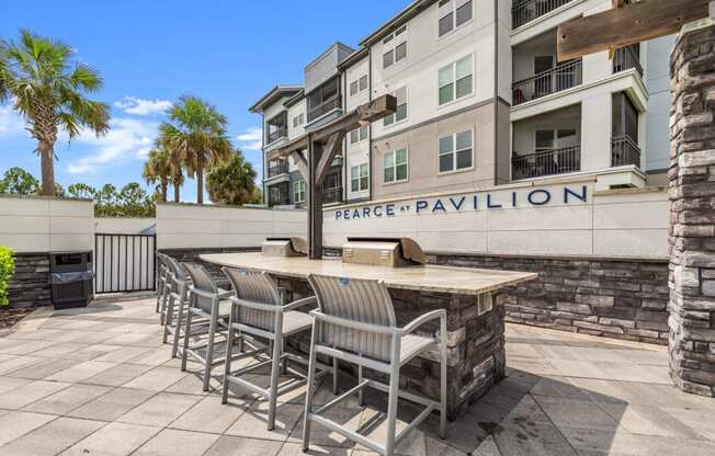 a patio with a bar and chairs in front of an apartment building