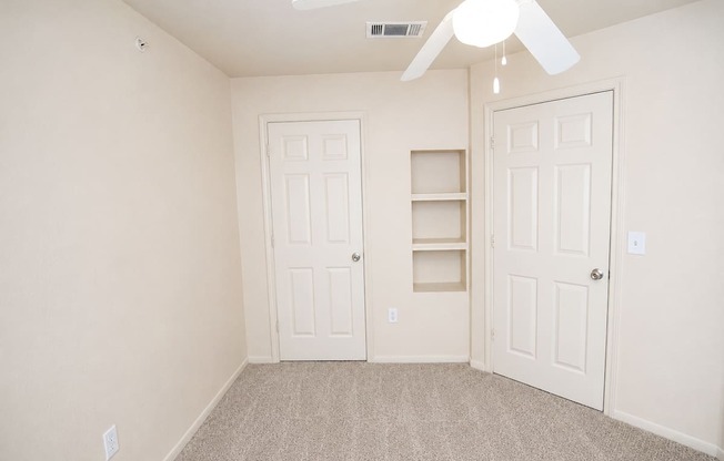 A room with a ceiling fan and two doors.