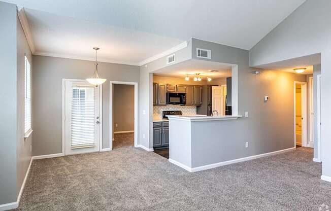A spacious living room with a kitchen area in the background.