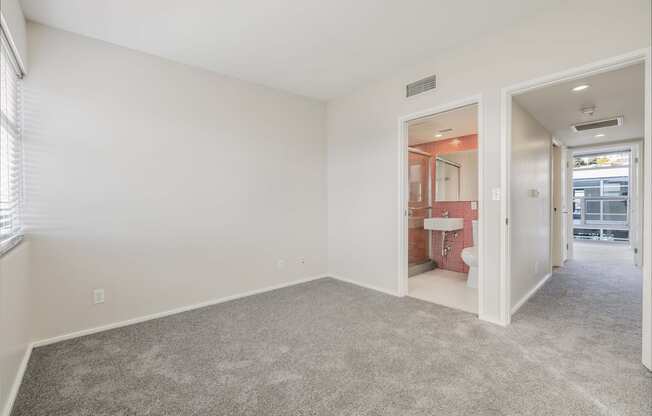 A room with a carpeted floor and a bathroom visible through an open door.