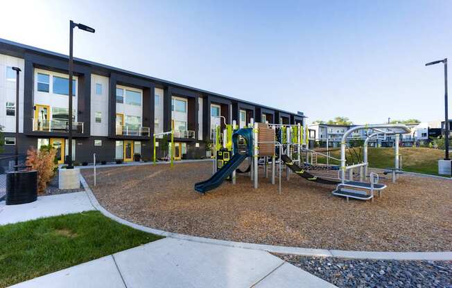 A playground with a green slide and a yellow railing.