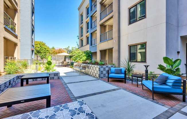 A patio area with blue couches and a brick floor.