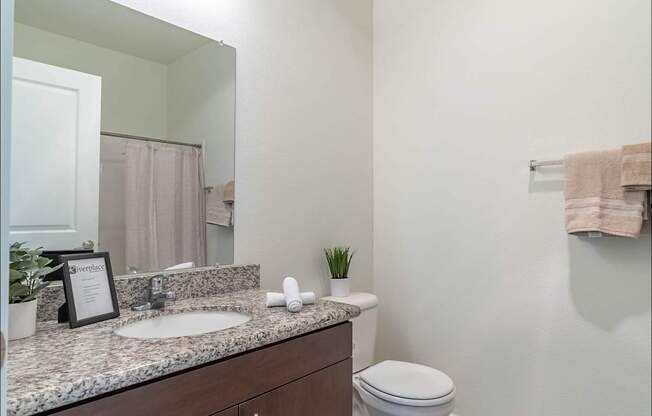 A bathroom with a white toilet and a marble counter top at Riverplace Apartment Homes, Independence, Oregon