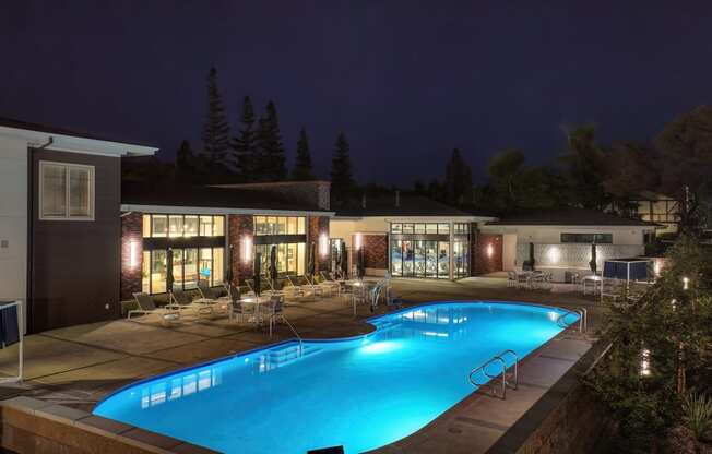 Community Swimming pool area at night with community clubhouse in the distance.