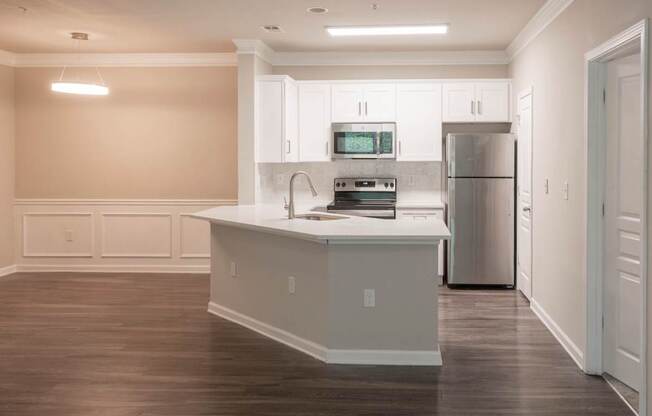 A kitchen with white cabinets and a wooden floor.