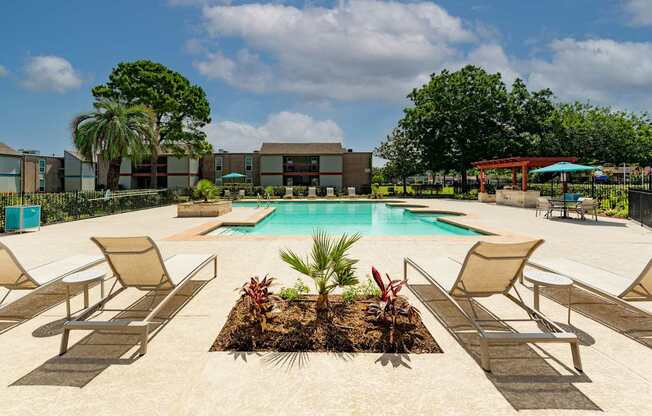 A pool surrounded by chairs and plants with a building in the background.