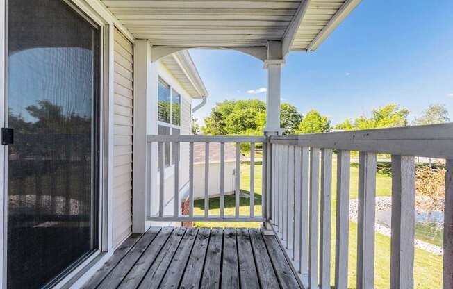 A porch with a white railing and a wooden floor.