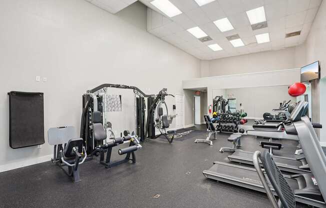A gym with a variety of equipment including treadmills, weights, and exercise machines.