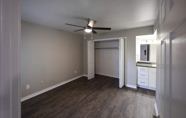 View of bedroom with bi-fold door closet, ceiling fan, and view of bathroom vanity