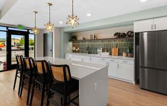 A kitchen with a white counter and black chairs.
